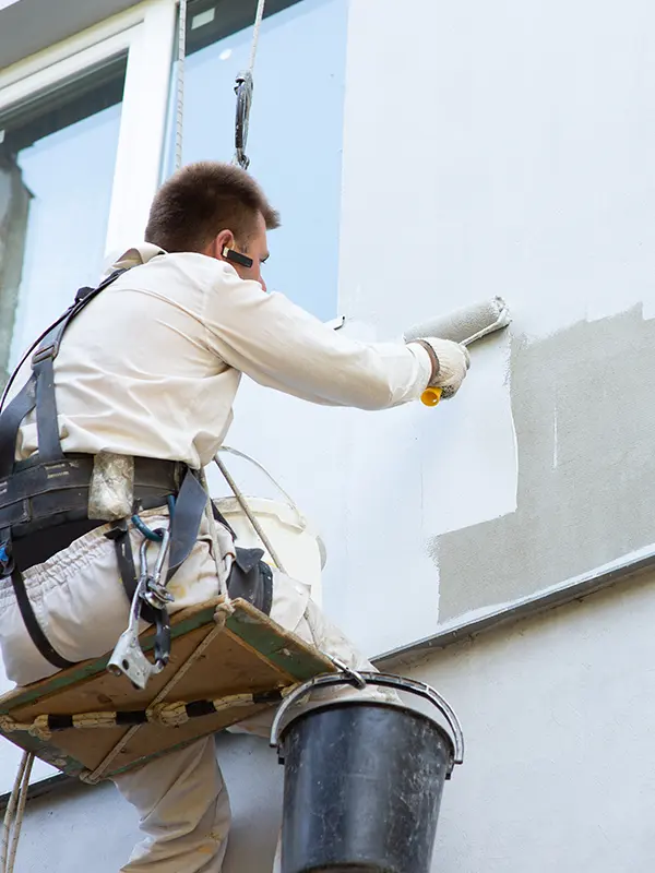 Arbeiter streicht Fassade grau